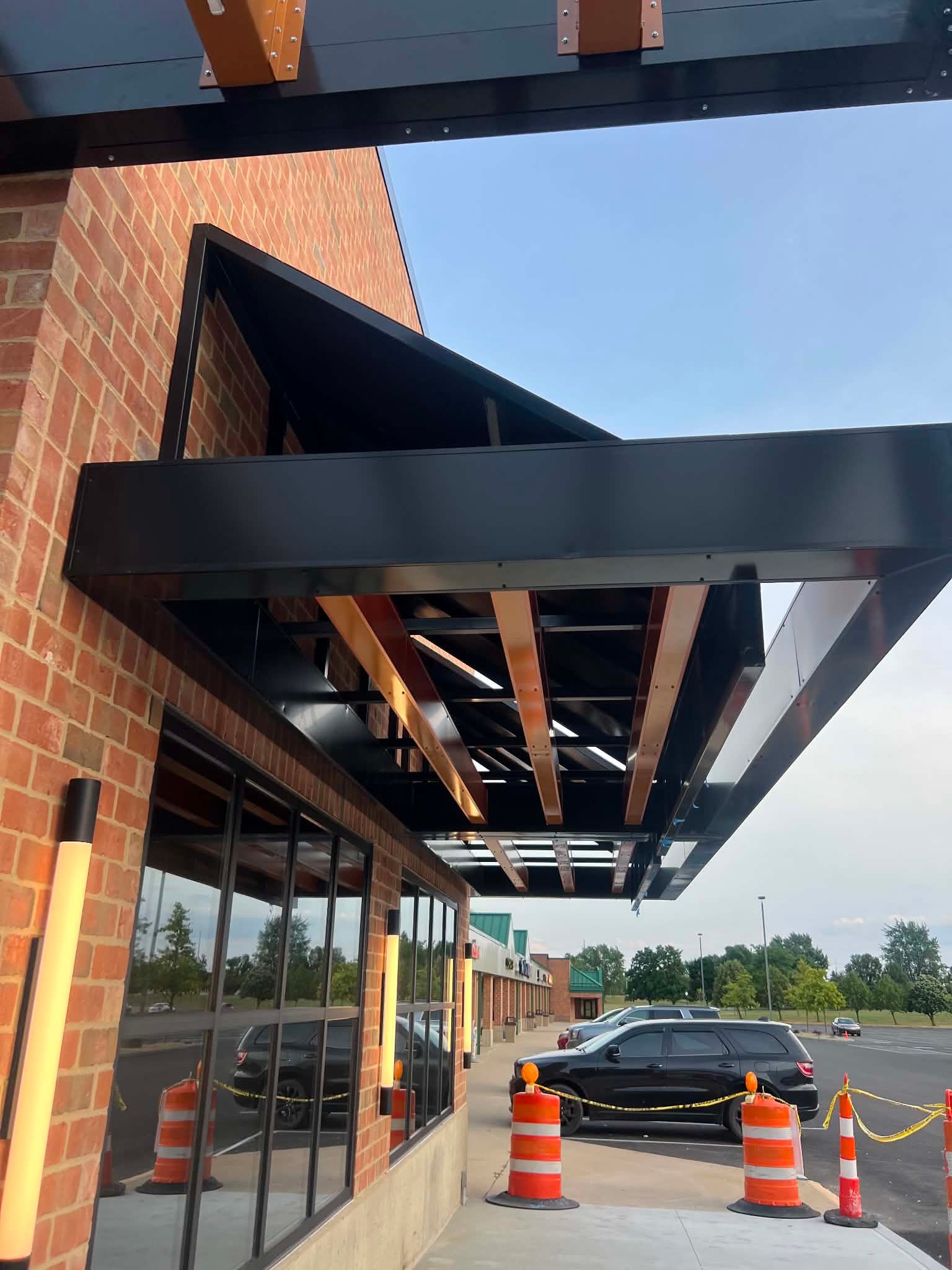 Black metal canopy with a warm wood soffit on a brick commercial building, built by Metal AP