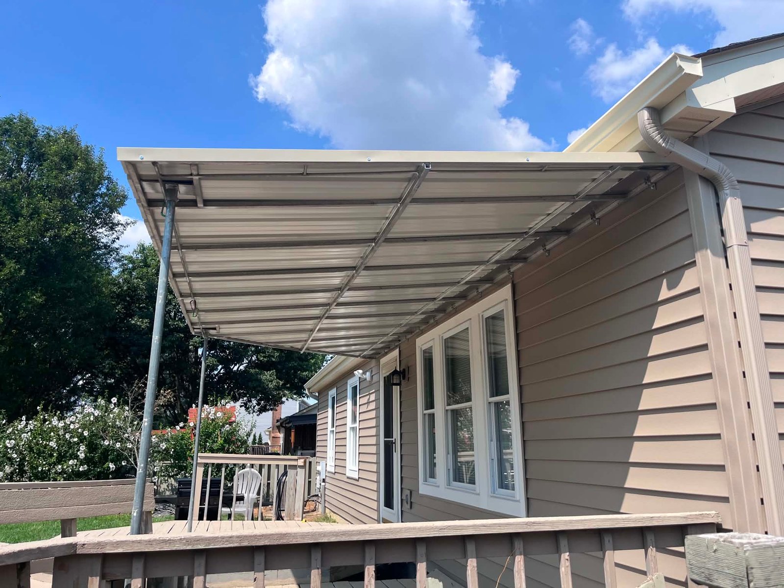 Custom metal cover over a residential deck with a blue sky behind